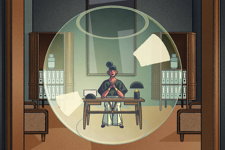 A female leader sits in a fishbowl within her office.