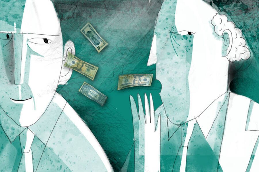 A man talks into another man's ear as money flies from his mouth