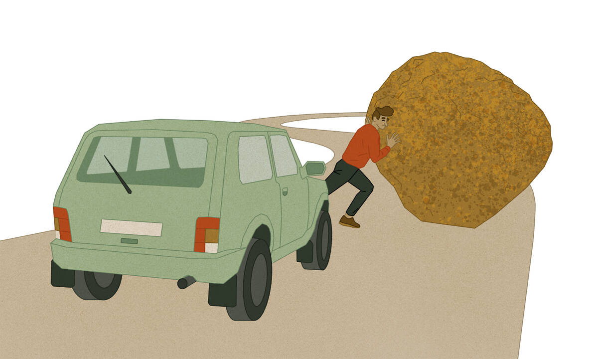 man pushing boulder away from road in front of car