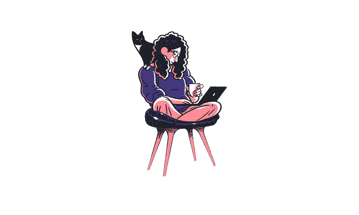 Woman in comfortable chair looking at laptop with cat on her shoulder