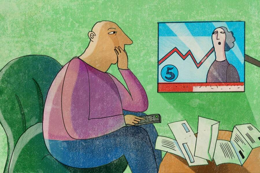 man watches business report on television with bills on table