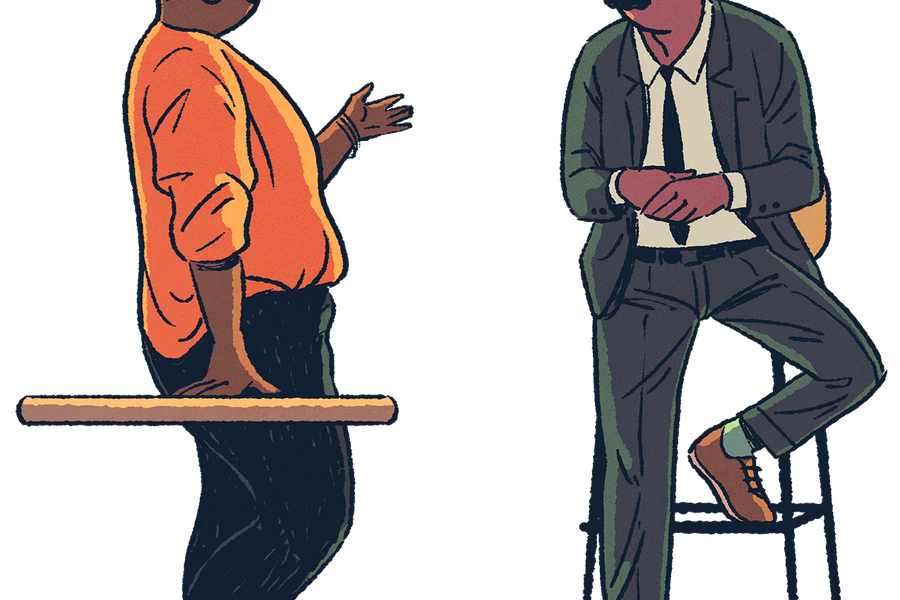standing woman speaking with man seated on stool