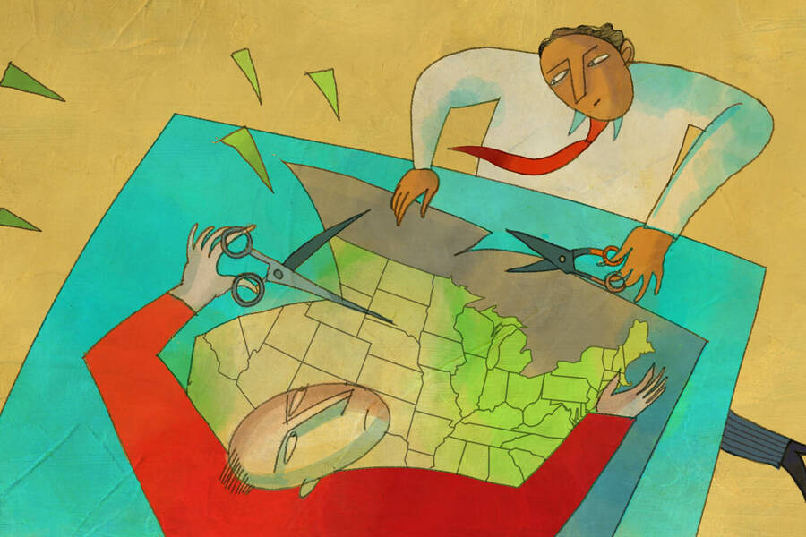 two people cut a U.S. map with scissors
