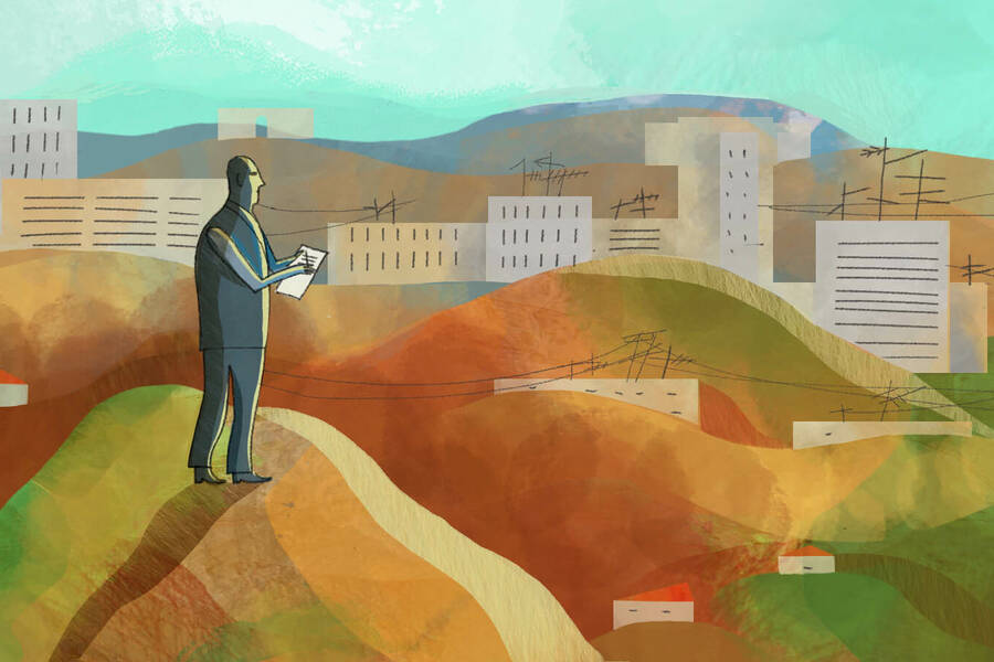 man standing on hilltop overlooking city